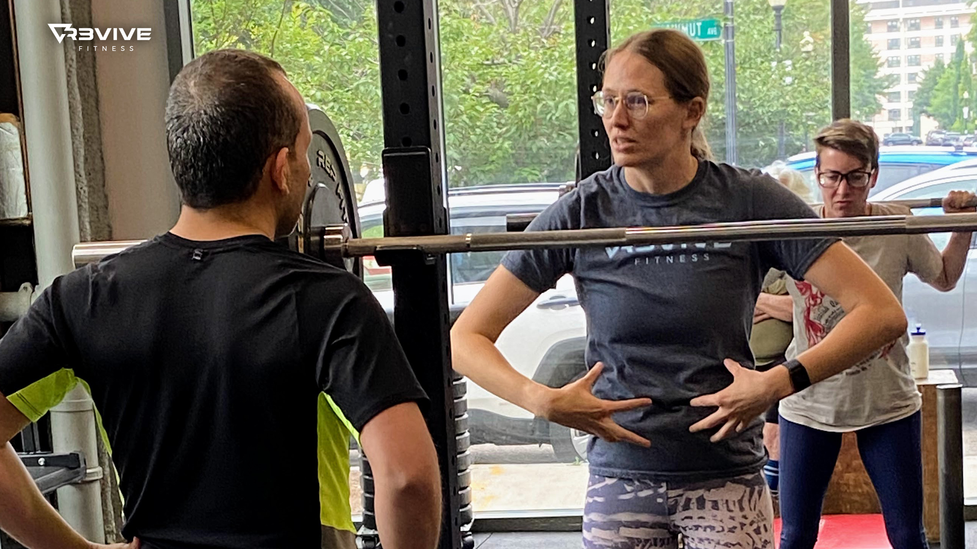 A coach instructing a member on how to use their core for squatting.